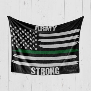 Op de afbeelding: Een zwart-witte gehaakte deken met een groene streep en de woorden "Army Strong" in wit. De deken heeft een ontwerp dat lijkt op de Amerikaanse vlag.