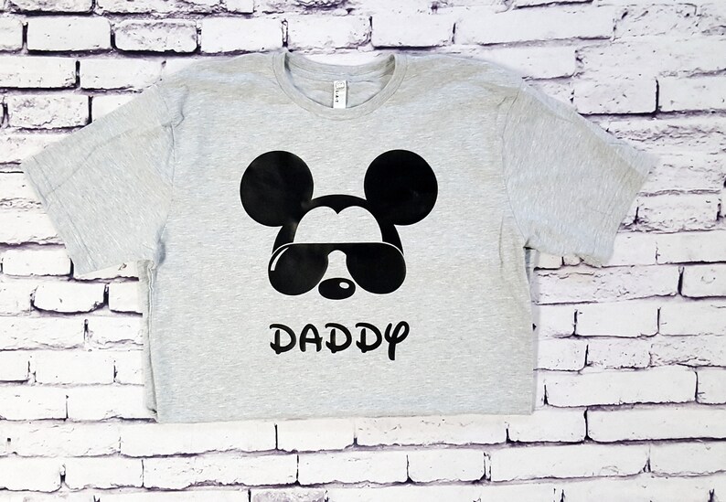May include: A gray t-shirt with a black Mickey Mouse design wearing sunglasses and the word "DADDY" underneath.