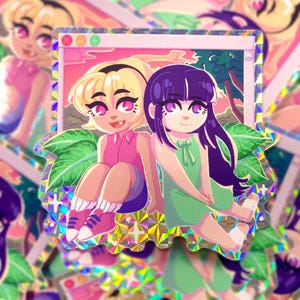 Peut inclure: Un autocollant holographique représentant une illustration de style anime de deux personnages assis dans le cadre d'une fenêtre informatique. Un personnage a des cheveux blonds et un haut rose, l'autre a de longs cheveux violet foncé.