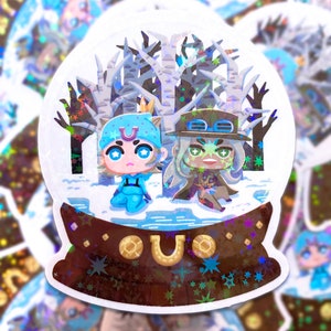 May include: A holographic sticker featuring two anime-style characters inside a snow globe. The characters are in a snowy scene with birch trees. The snow globe base is brown with gold accents and a horseshoe.