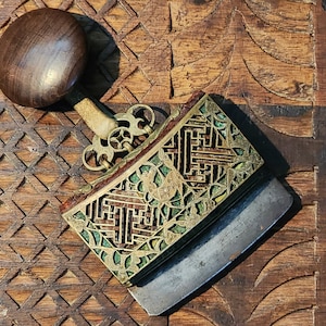 May include: A vintage, ornate, brass and steel fire starter with a wooden handle. The fire starter has intricate geometric designs and green accents.