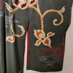 May include: A green kimono with a floral pattern. The kimono has a red trim and is decorated with gold and brown flowers.