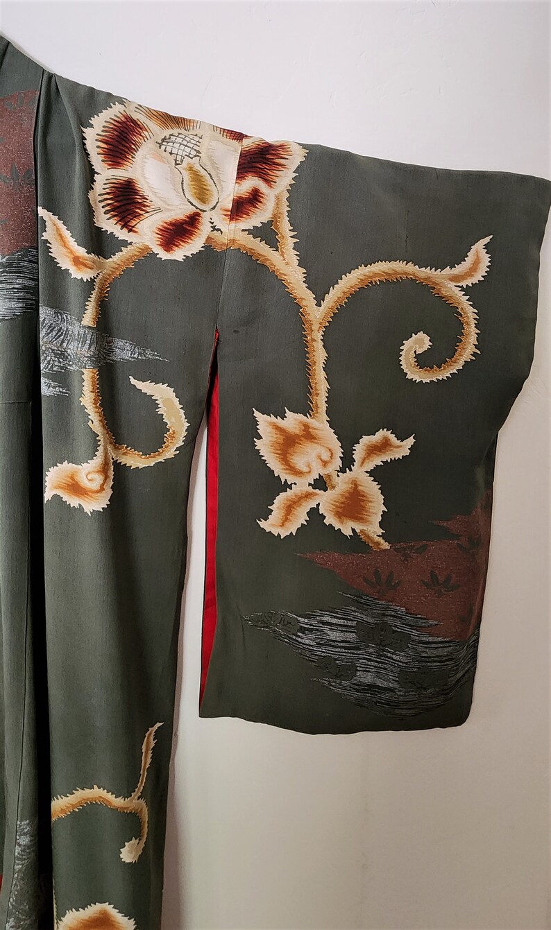 May include: A green kimono with a floral pattern. The kimono has a red trim and is decorated with gold and brown flowers.