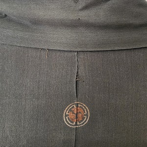 May include: A dark green kimono with a brown and gold embroidered circle design on the back.