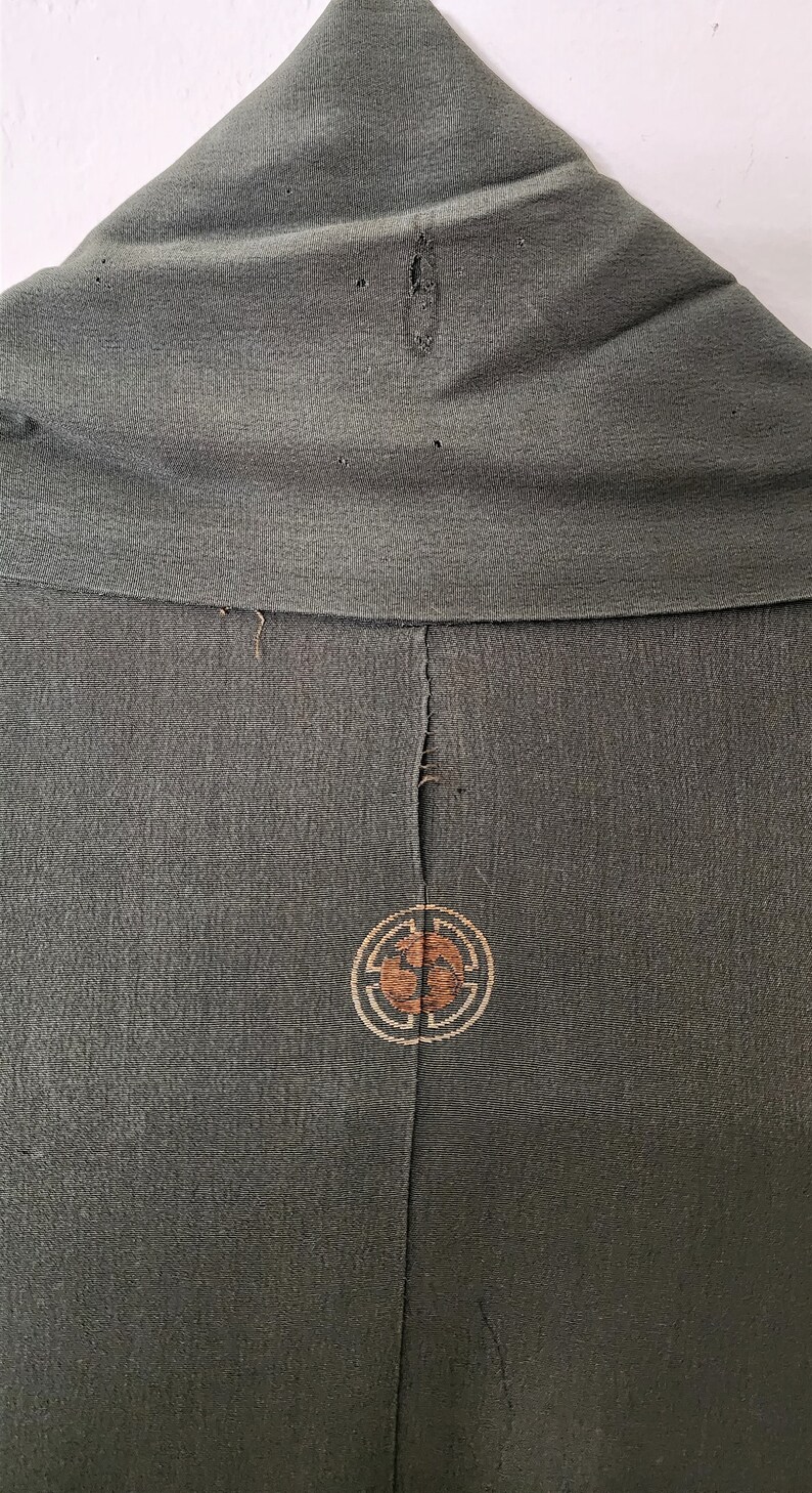 May include: A dark green kimono with a brown and gold embroidered circle design on the back.