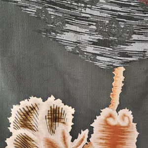 May include: A green fabric with a brown and white floral pattern. The fabric has a textured surface and a subtle sheen.