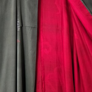 May include: A green kimono with a red lining. The kimono has a floral pattern on the sleeve and a geometric pattern on the front.