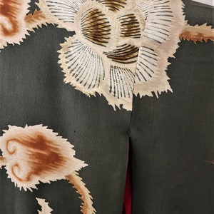 May include: A dark green fabric with a white and brown floral pattern. The fabric has a textured surface and a red seam down the center.
