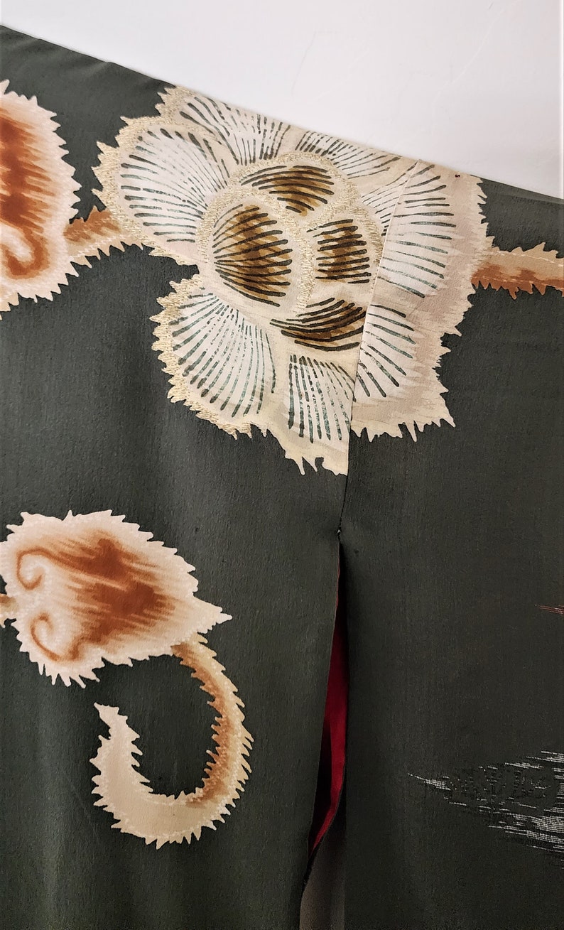 May include: A dark green fabric with a white and brown floral pattern. The fabric has a textured surface and a red seam down the center.