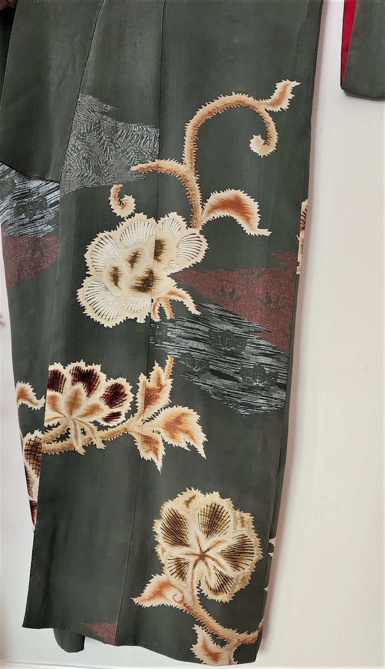 May include: A dark green kimono with a floral pattern in shades of brown, white, and red. The kimono has a traditional Japanese design with intricate details.