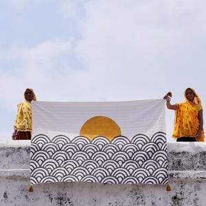 Peut inclure: Une tenture murale rectangulaire en textile pr&eacute;sentant un fond blanc avec un grand cercle dor&eacute; uni repr&eacute;sentant le soleil, plac&eacute; au-dessus d'un motif r&eacute;p&eacute;titif de demi-cercles gris fonc&eacute; superpos&eacute;s &eacute;voquant des vagues stylis&eacute;es.
