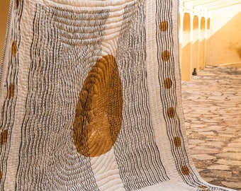 May include: A white cotton quilt with a black and brown geometric pattern. The quilt has a large brown circle in the center and a border of small brown circles.