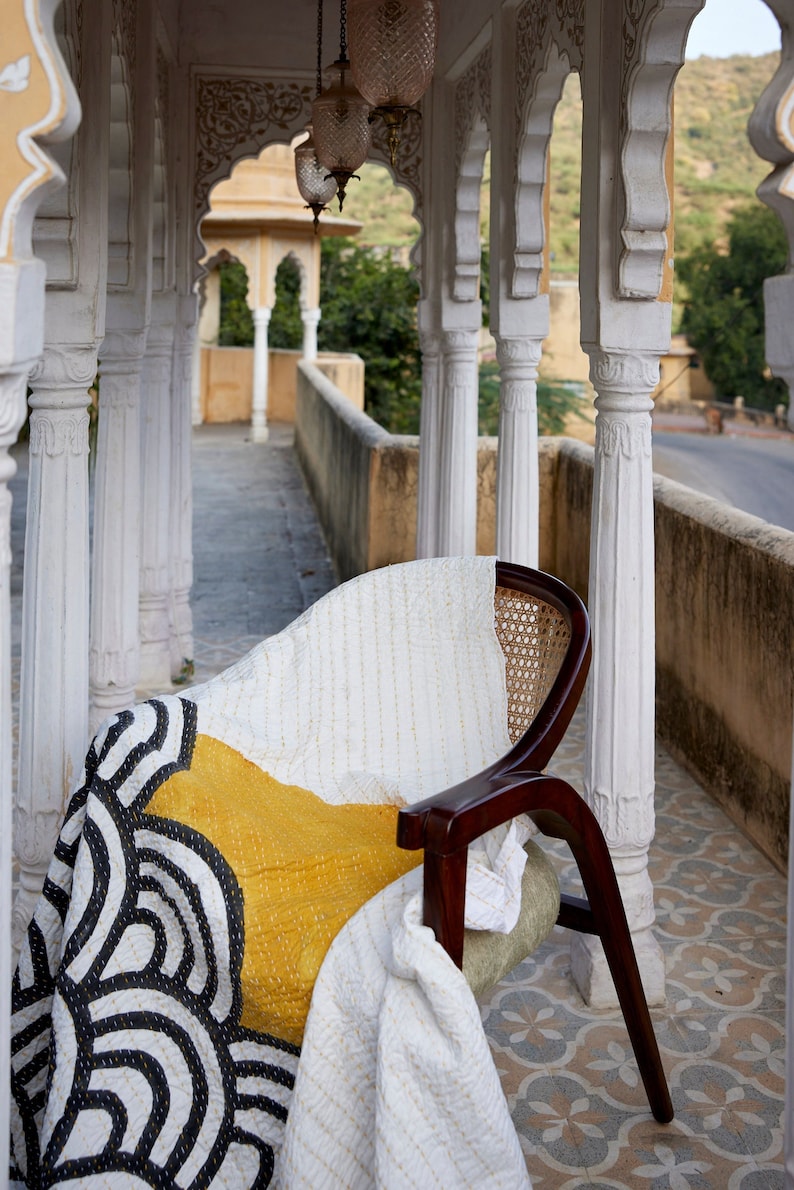 Peut inclure: Une chaise en bois fonc&eacute; avec un dossier en cannage et un coussin d'assise vert clair, recouverte d'une courtepointe blanche orn&eacute;e d'un grand bloc jaune moutarde et de motifs de lignes arqu&eacute;es noires avec des surpiq&ucirc;res blanches visibles.