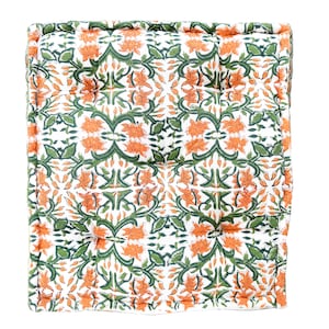 May include: A square floor cushion with a white background and a repeating pattern of orange and green floral designs.