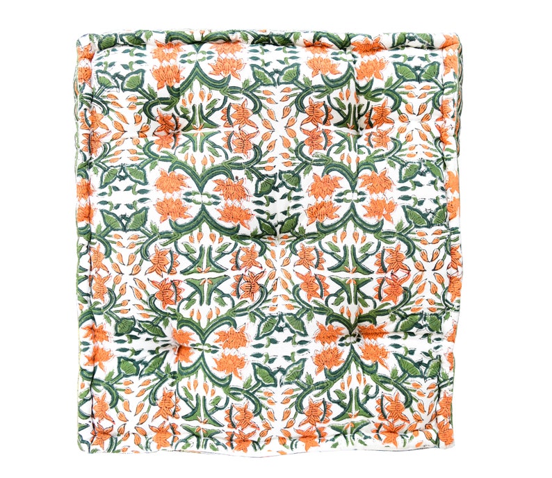 May include: A square floor cushion with a white background and a repeating pattern of orange and green floral designs.