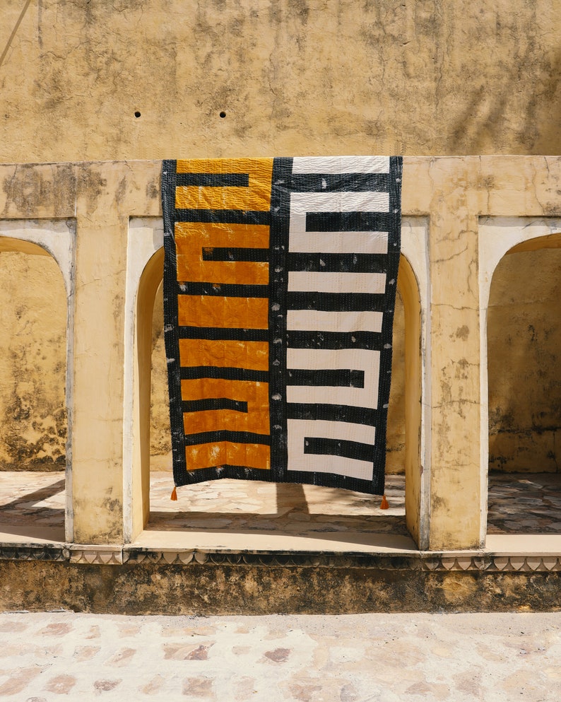 May include: A black and white geometric patterned fabric hanging in a doorway with a yellow and black geometric patterned fabric hanging next to it.