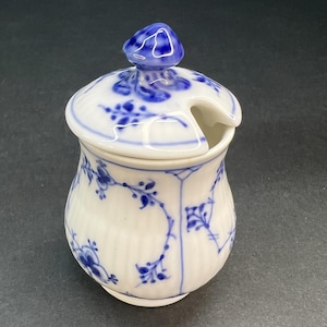 Könnte beinhalten: Eine weiße Zuckerdose aus Keramik mit einem blauen und weißen Blumenmuster. Die Dose hat einen Deckel mit einem kleinen Ausgießer.