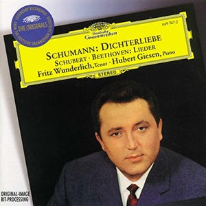 May include: A CD cover featuring a portrait of a man in a suit and tie. The cover has a yellow banner with the text "SCHUMANN: DICHTERLIEBE" and other musical details. The Deutsche Grammophon logo is visible.