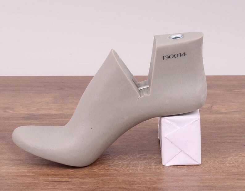 May include: A gray shoe last with a high heel and a pointed toe. The last has a number "130014" printed on the side.