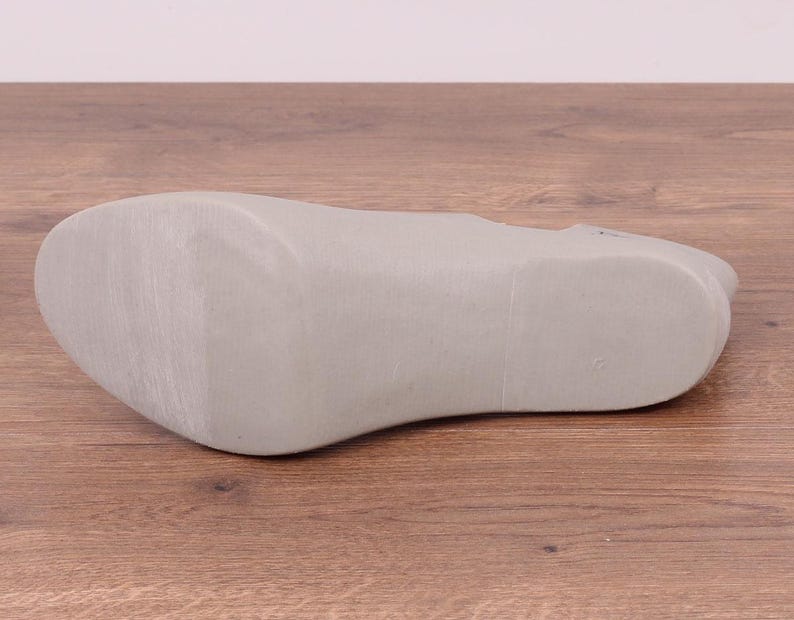 May include: The bottom of a light gray shoe with a smooth, textured sole.