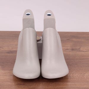 May include: Two gray shoe trees made of plastic. The shoe trees are designed to help maintain the shape of shoes.