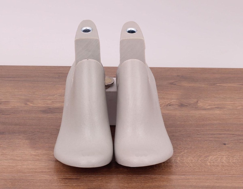 May include: Two gray shoe trees made of plastic. The shoe trees are designed to help maintain the shape of shoes.