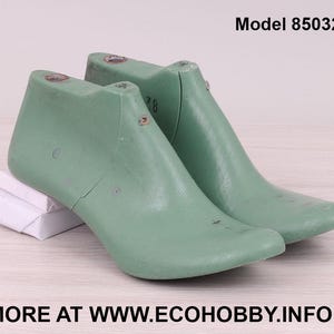 May include: A pair of green shoe lasts, used for making shoes, with the model number 85032 printed on the background.