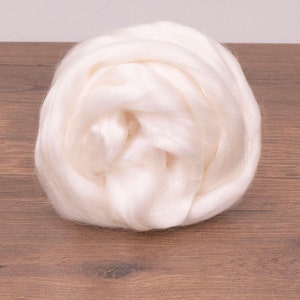 May include: A close-up of a white, fluffy ball of natural silk fiber. The silk is soft and delicate, and it is perfect for spinning, weaving, or felting.