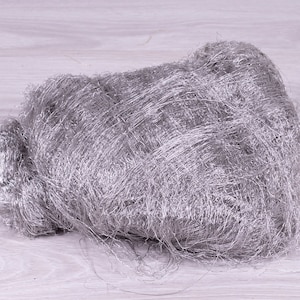 May include: A pile of silver-colored steel wool. The steel wool is loose and fluffy, and it is arranged in a loose, irregular shape.