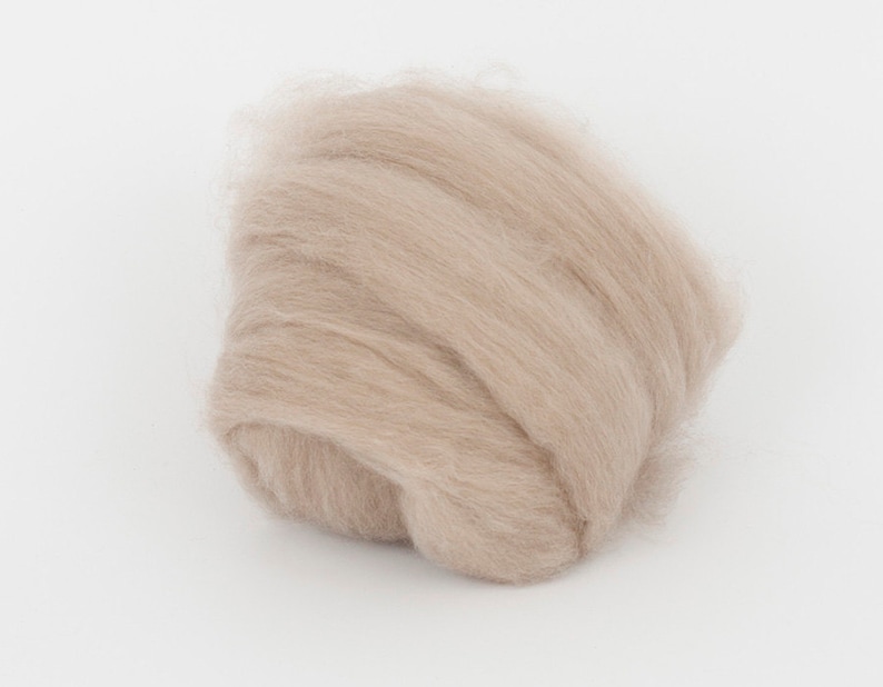May include: A mass of light tan wool fibers, tightly packed and slightly curled. The fibers have a soft, fluffy appearance, suggesting a natural textile material. The wool is likely used for crafting or textile projects.
