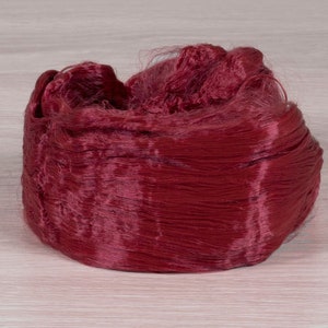 May include: A close-up of a deep red spool of thread. The thread is soft and silky, and it is wound tightly around the spool.