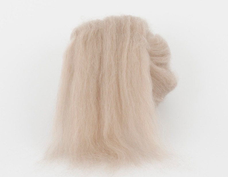 May include: A light beige, fluffy material, possibly yarn or fiber, is displayed against a white background. The material appears soft and delicate, with a slightly ruffled texture. The overall impression is of a natural, airy textile.
