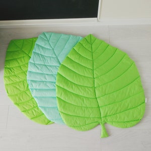 May include: Three leaf-shaped play mats in green, light green, and turquoise. The mats are quilted and have a leaf vein pattern.