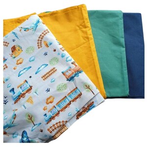 Puede incluir: Cuatro cuadrados de tela, uno con un patrón de tren azul y blanco, uno amarillo, uno verde y uno azul.