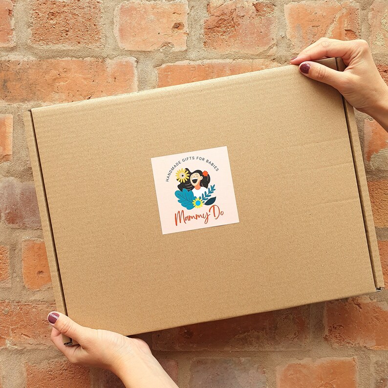 May include: A brown cardboard box with a sticker that says "Handmade gifts for babies Mommy Do" with a cartoon illustration of a woman with flowers and a blue background.