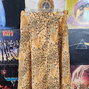 May include: A brown and black leopard print skirt with a button closure. The skirt is knee-length and has a flowy silhouette.