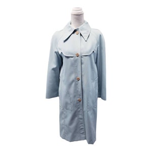 May include: A light blue trench coat with a classic design. The coat features a collared neckline, button-down front, and two front pockets. The coat is displayed on a mannequin and has a knee-length hemline.