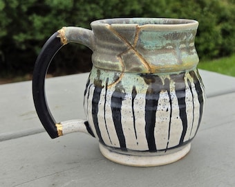 Black and white striped functional handmade ceramic coffee or tea mug kintsugi inspired with real gold.
