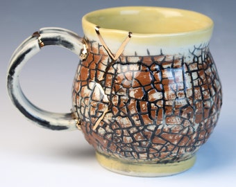 Kintsugi, Wabi Sabi, functional handmade yellow brown and gold ceramic coffee or tea mug with cracked texture and decorative 22k gold repair