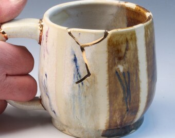 Kintsugi, Wabi Sabi, functional handmade yellow brown and gold ceramic coffee or tea mug with poured pattern and decorative 22k gold repair