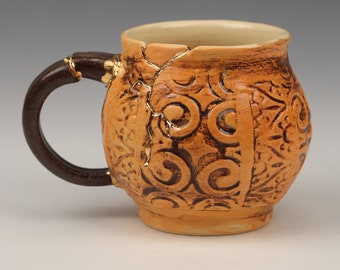 Kintsugi, Wabi Sabi, functional handmade rusty orange ceramic coffee or tea mug with stamped texture and decorative real 22k gold repair