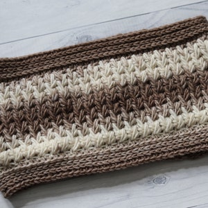 May include: A brown and cream crocheted headband with a textured stitch pattern.