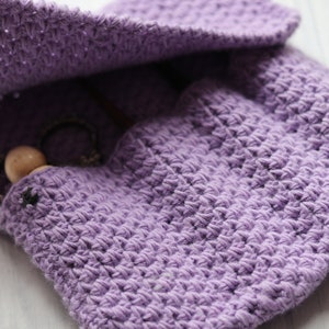 May include: A purple crocheted pouch with a wooden bead and a metal chain inside. The pouch is open and the lining is visible.