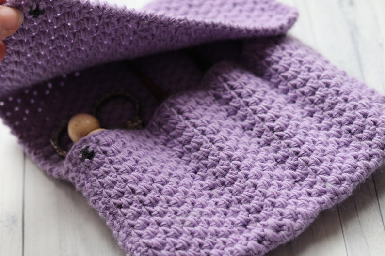 May include: A purple crocheted pouch with a wooden bead and a metal chain inside. The pouch is open and the lining is visible.