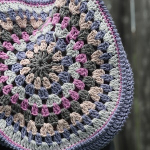 May include: A crocheted circular rug with a multi-colored design featuring shades of pink, gray, and blue.