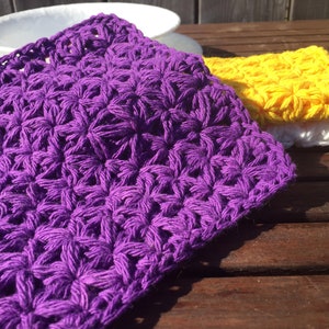 May include: Three crocheted dishcloths in purple, yellow, and white. The dishcloths are made with a star stitch pattern.