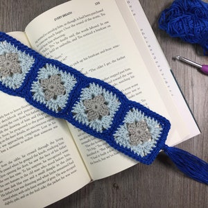 May include: A blue and gray crocheted bookmark with a tassel. The bookmark is made of granny squares and features a blue tassel.