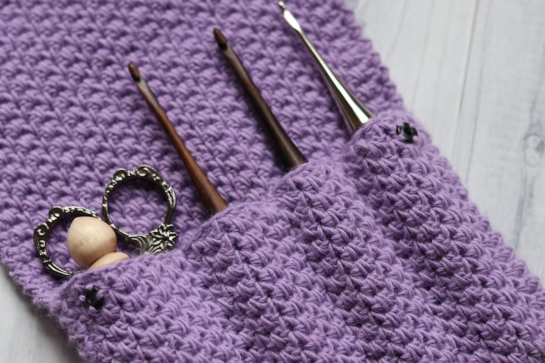 May include: Purple crocheted pouch with three crochet hooks and a pair of vintage scissors with a wooden knob.