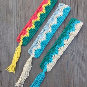 May include: Three crocheted bookmarks with colorful chevron patterns and tassels. The bookmarks are in shades of red, yellow, green, blue, and white.