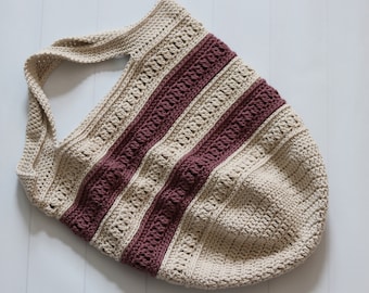 May include: A crocheted tote bag with a striped design in beige and burgundy. The bag has a wide, open top and a single handle.